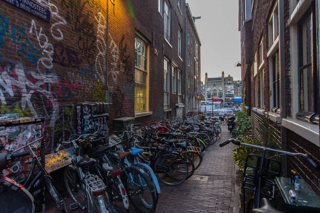Bicycles parked along a narrow city street lined with graffiti