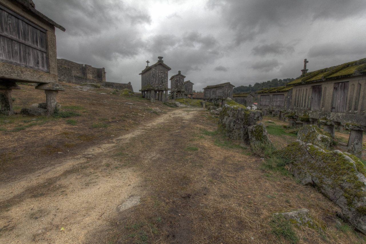 A dirt path leading between rows of old stone granaries
